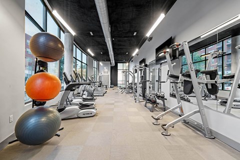 a gym with weights and other exercise equipment in a building with large windows